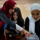 Muslim woman helps refugee student load information into an iPad Article 26 Backpack UC Davis
