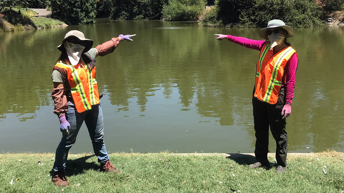 Two people with bandanas point to bubbles in Lake Spafford.
