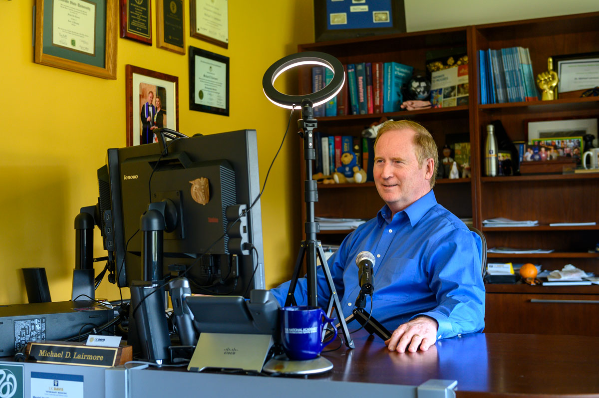 Michael Lairmore at desk with computer, microphone and lighting for podcast recording.