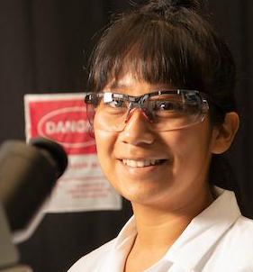 Student poses with microscope