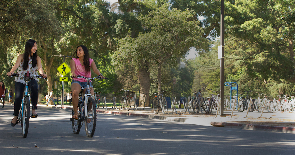 3.	Managerial Economics majors Kristi Juwono (floral shirt) and Anshita Jain (pink shirt) are photographed with their bikes near the Social Sciences building on July 1, 2016. ALthough both women are from Jakarta, Indonesia, they didn't become friends until meeting at UC Davis. They are both peer advisors.  Karin Higgins/UC Davis