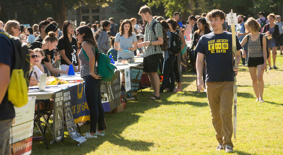 Students are outside in a field tabling to advertise their clubs. 