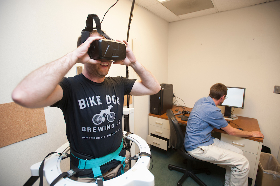 A man smiles in VR goggles in a lab. 