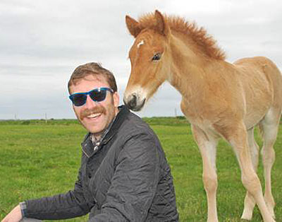 Erick Loomis in sunglasses with a foal behind him