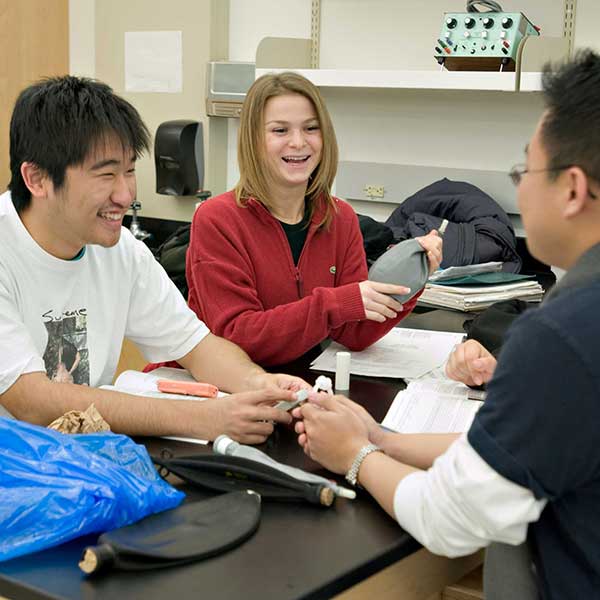 Three students talking and working on a project in a biology lab class