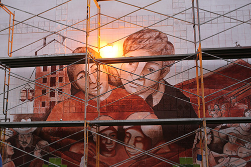 A mural of a man and woman with scaffolding in front