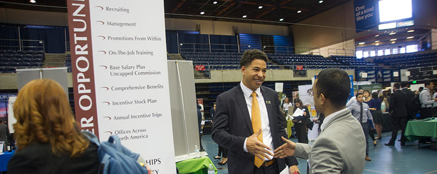 Two men talking in a big career fair with others milling about