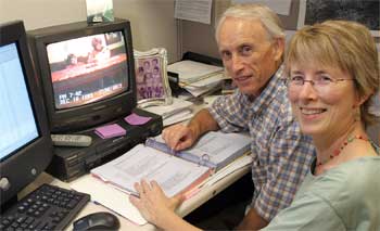 Photo: man and woman in front of computer looking at camera