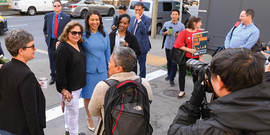 London Breed stops to take photos with city residents while walking to work