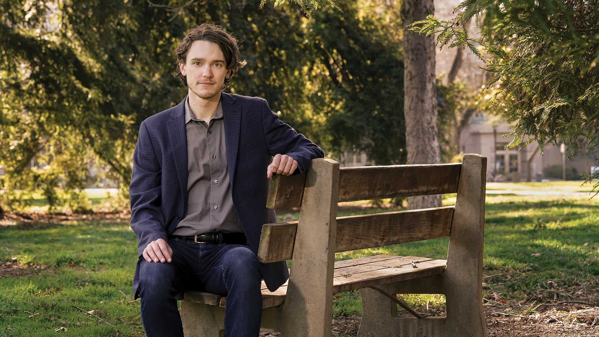 A student sits on a bench on the Quad