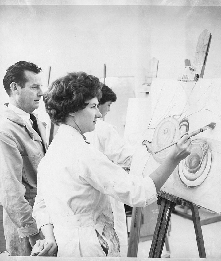 Photo: a man helps a woman with a painting