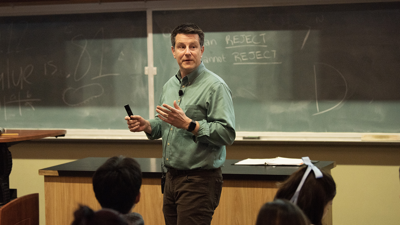 Jay Stachowicz walks in front of a classroom chalkboard