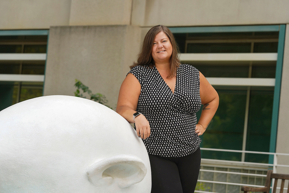 Katy Pattison smiles beside an egghead statue at UC Davis. 