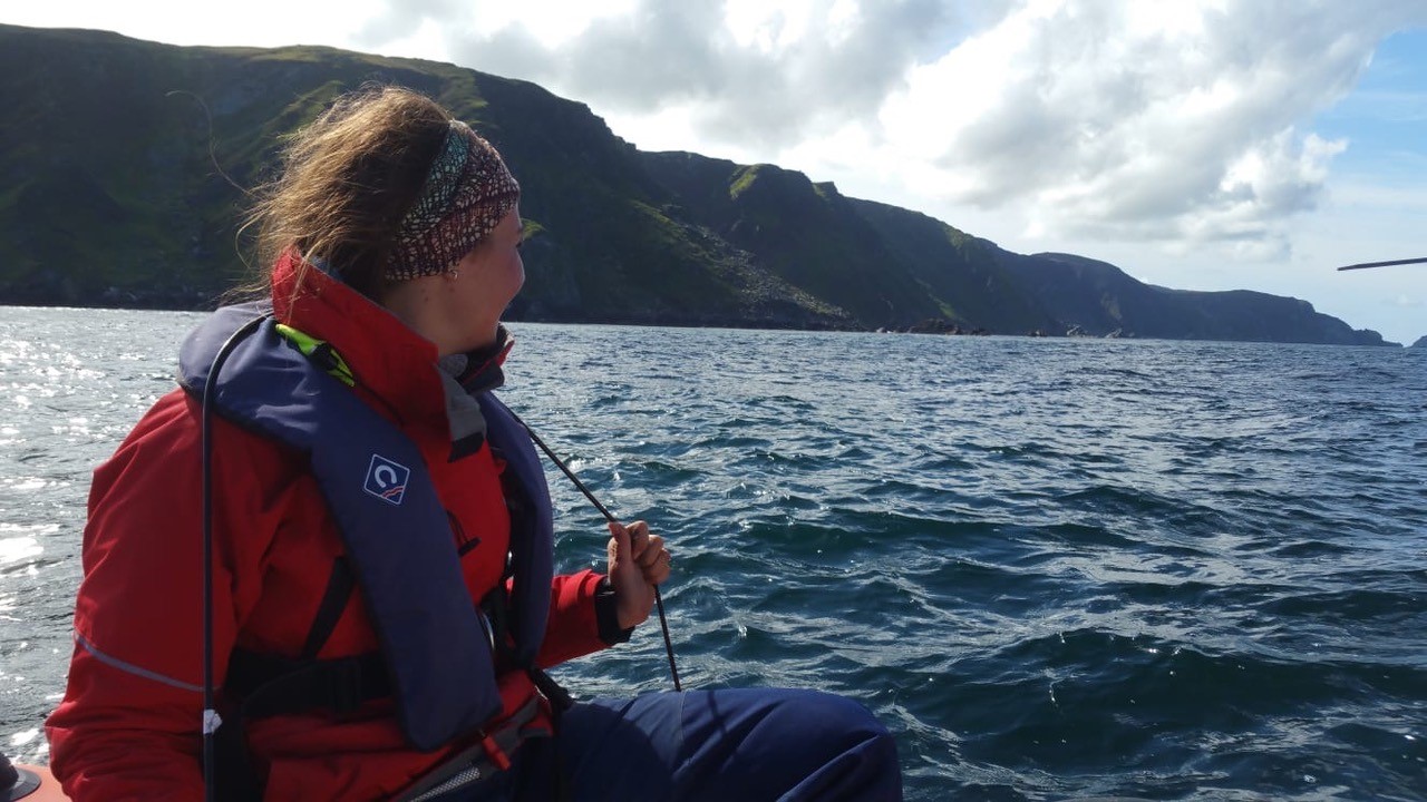 Scientist Alexandra McInturf in red jacket on boat looking out at choppy ocean