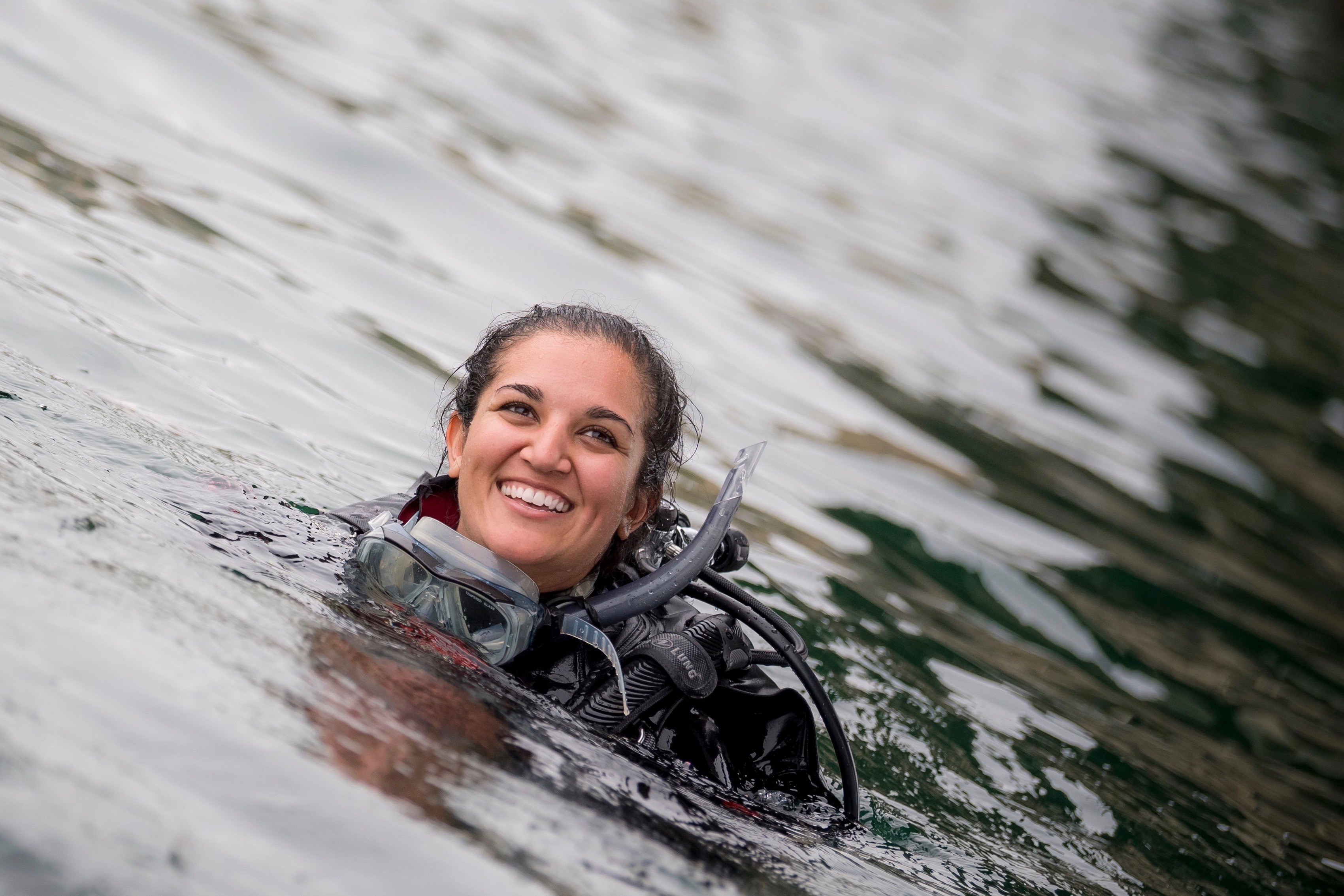 Woman scientists's head above water, smiling, during diving expedition
