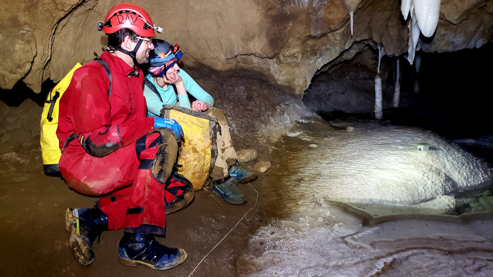 Researchers look at water dripping off a stalagmite inside a cave.