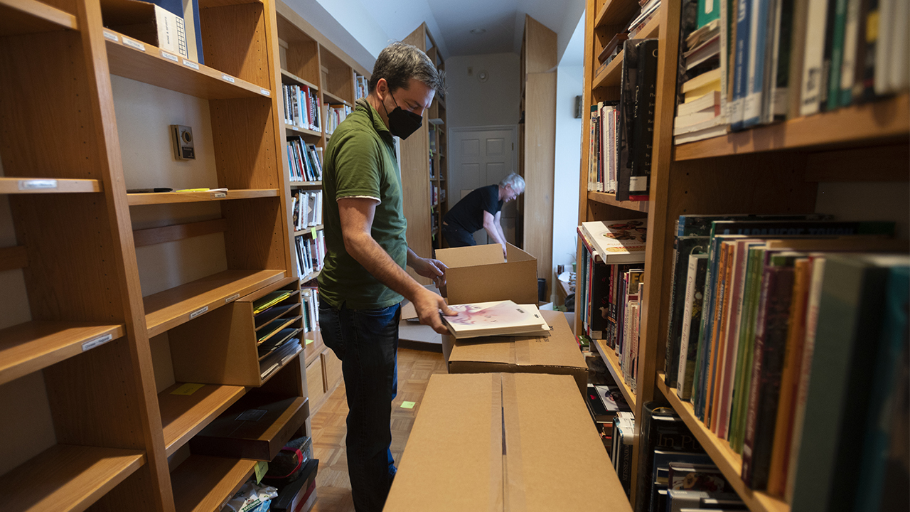 Two men and cardboard boxes among bookshelves