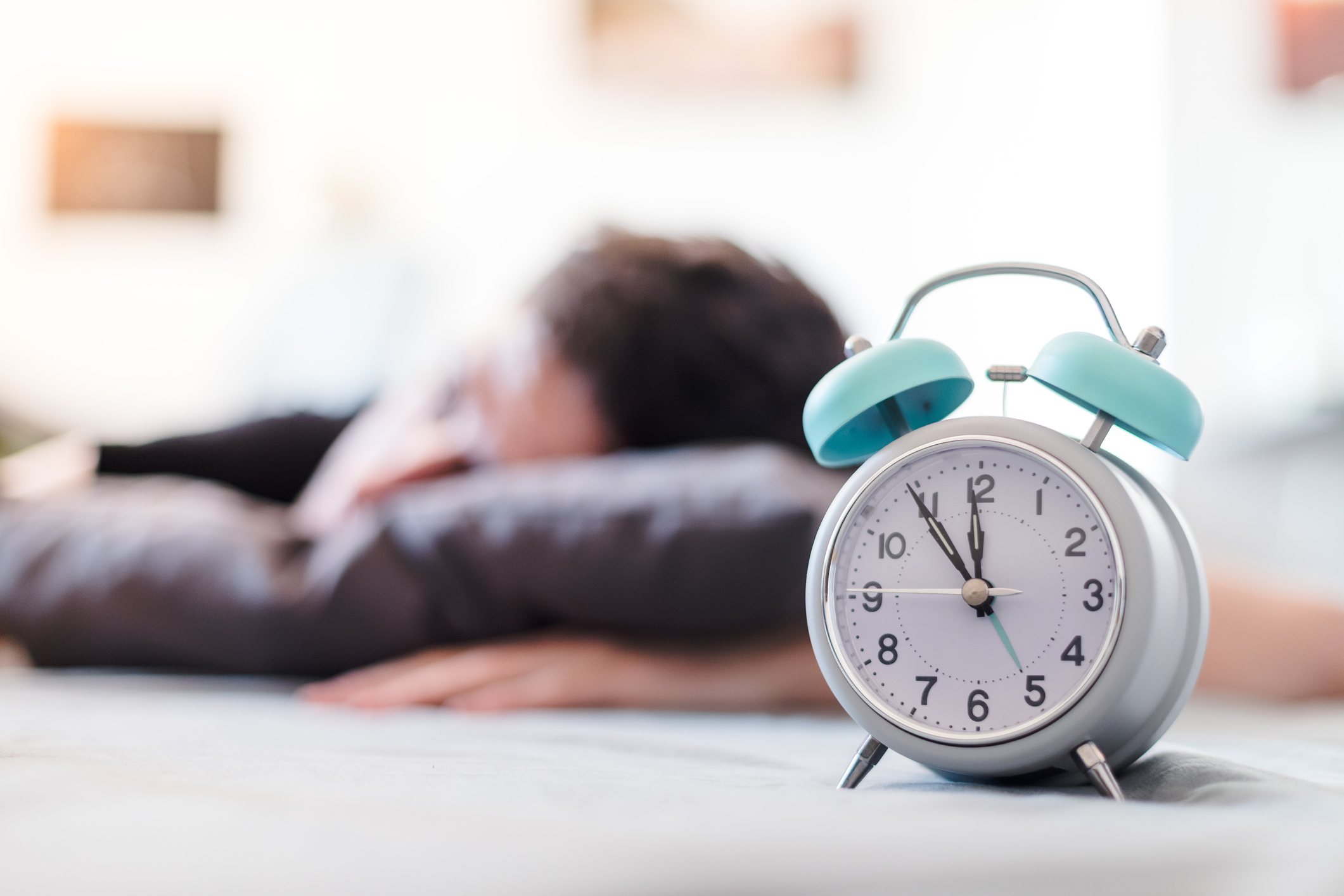 It can be tough on our bodies when we spring forward to daylight saving time. A UC Davis Health sleep expert offers strategies to help you adjust. Man shown sleeping behind the face of an alarm clock.