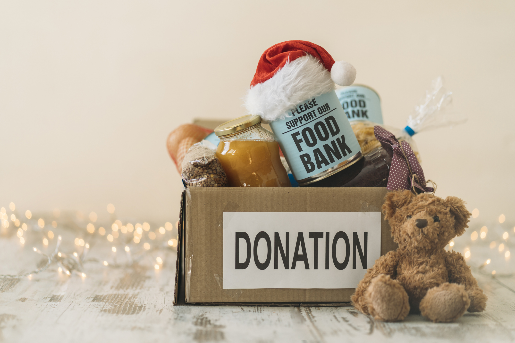 Box labeled donations with small Santa hat, food, stuffed bear