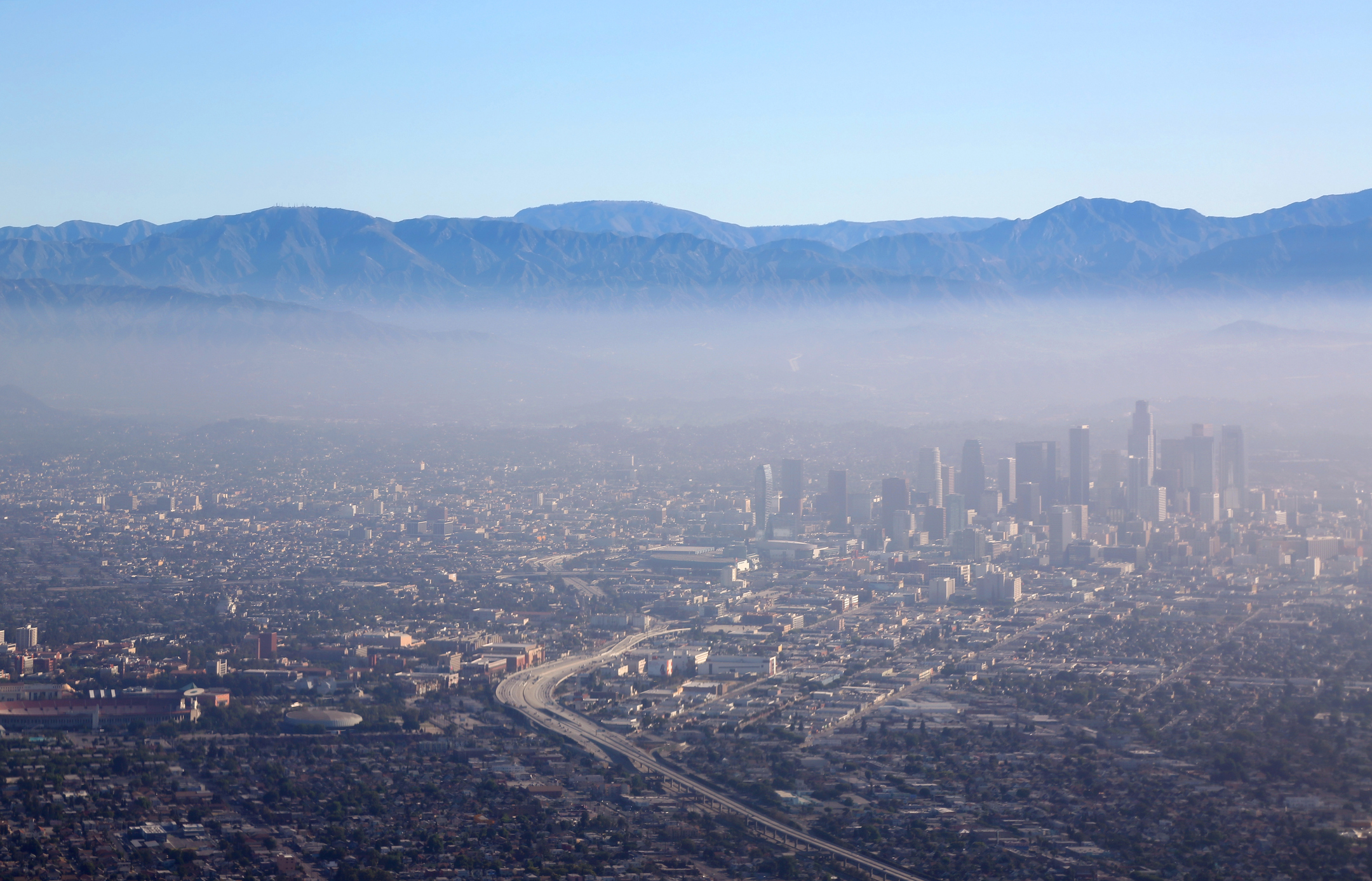 Smog settles over downtown Los Angeles with San Gabriel mountains in background