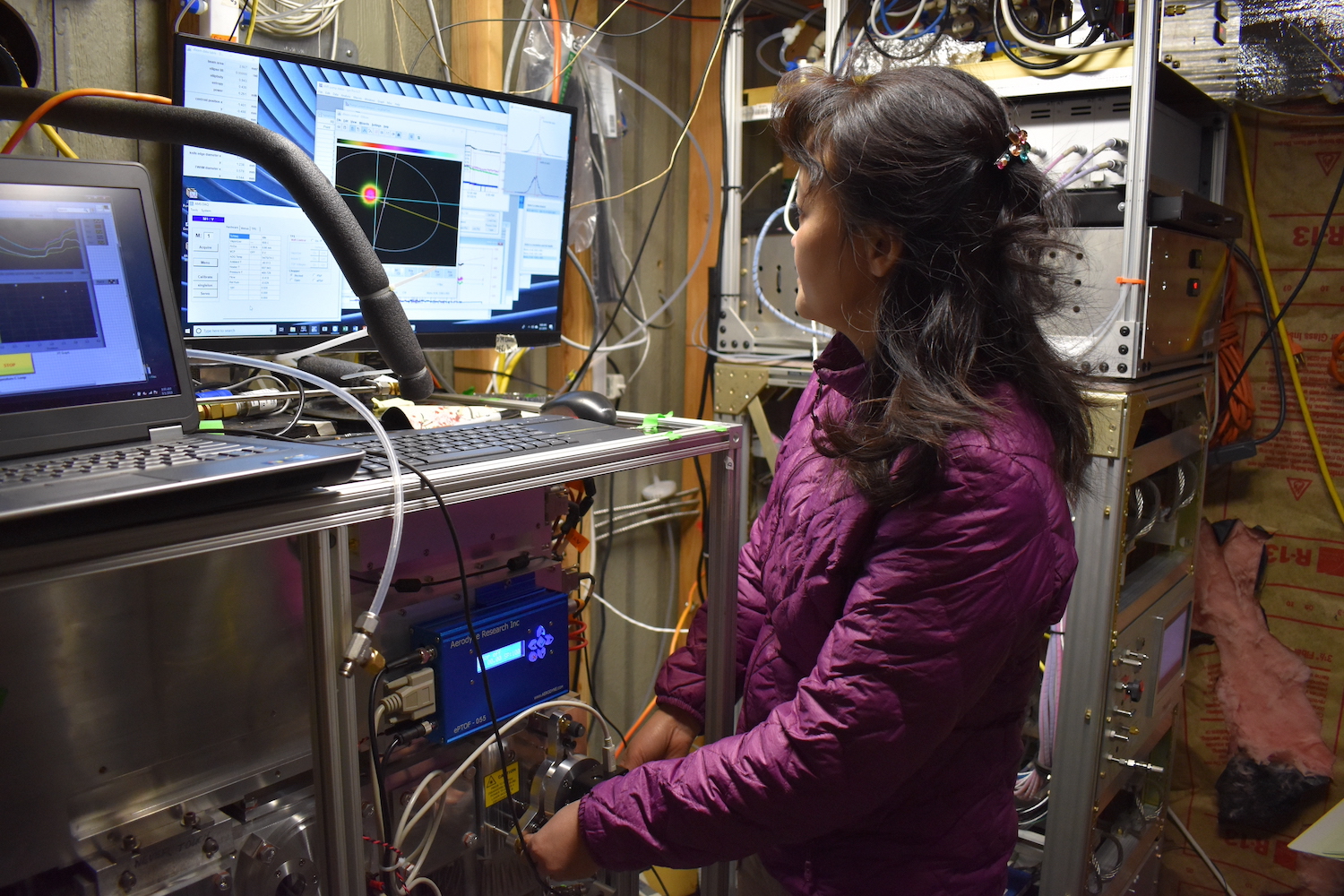 An Asian-American female scientist looks at the screen monitor of a laser vaporizer in a lab. 