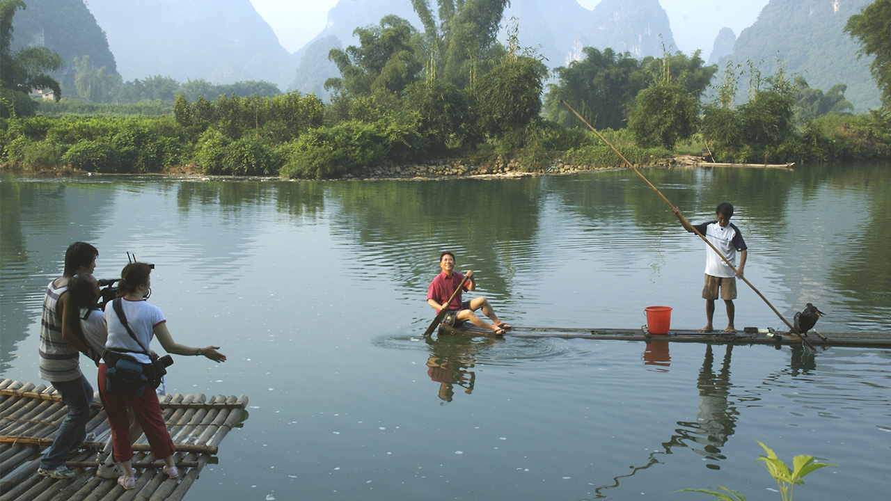 Crew films Martin Yan on small raft floating in river