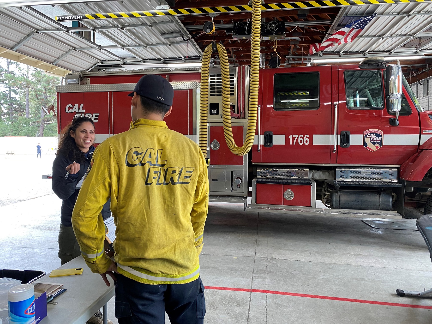 Woman interviewing CALFIRE employee about ticks in front of fire truck.