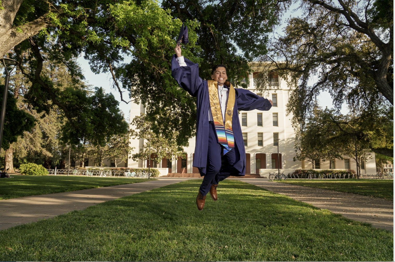 UC Davis grad jumps in front of Mrak Hall for a graduation picture