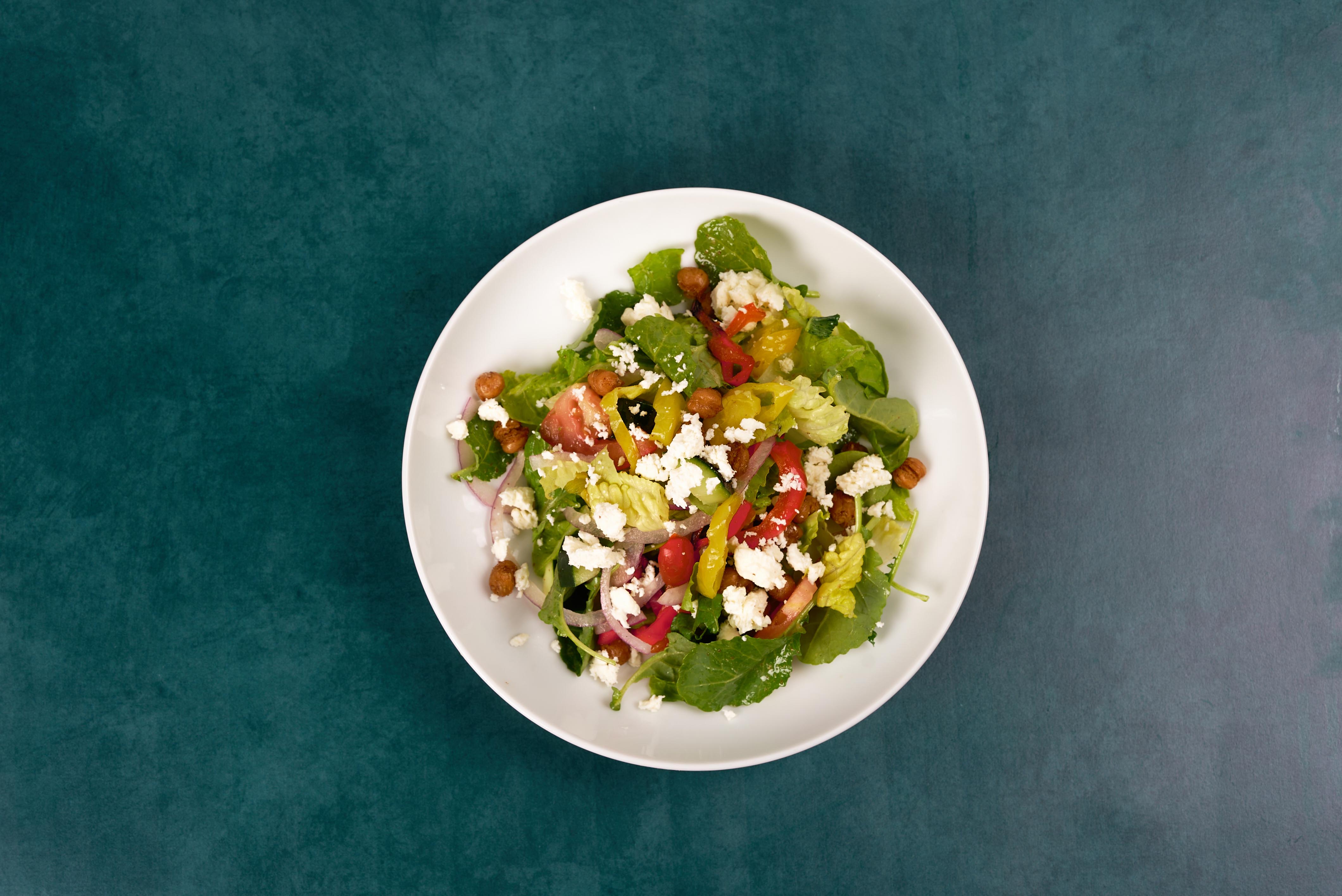 An overhead, birds-eye-view shot of a freshly prepared greek salad called the Triathlete Greek Salad.