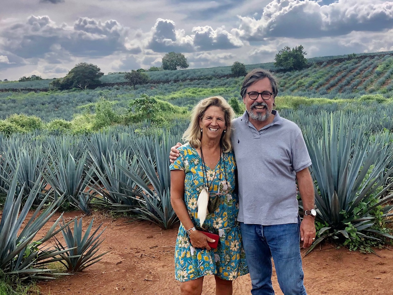 Two people stand in front of row of agave plants