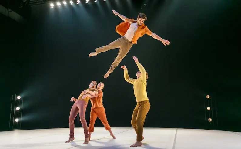 Dancers flying through air on stage. 