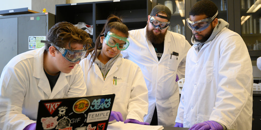 4 students look over their notes in a lab on campus at UC Davis