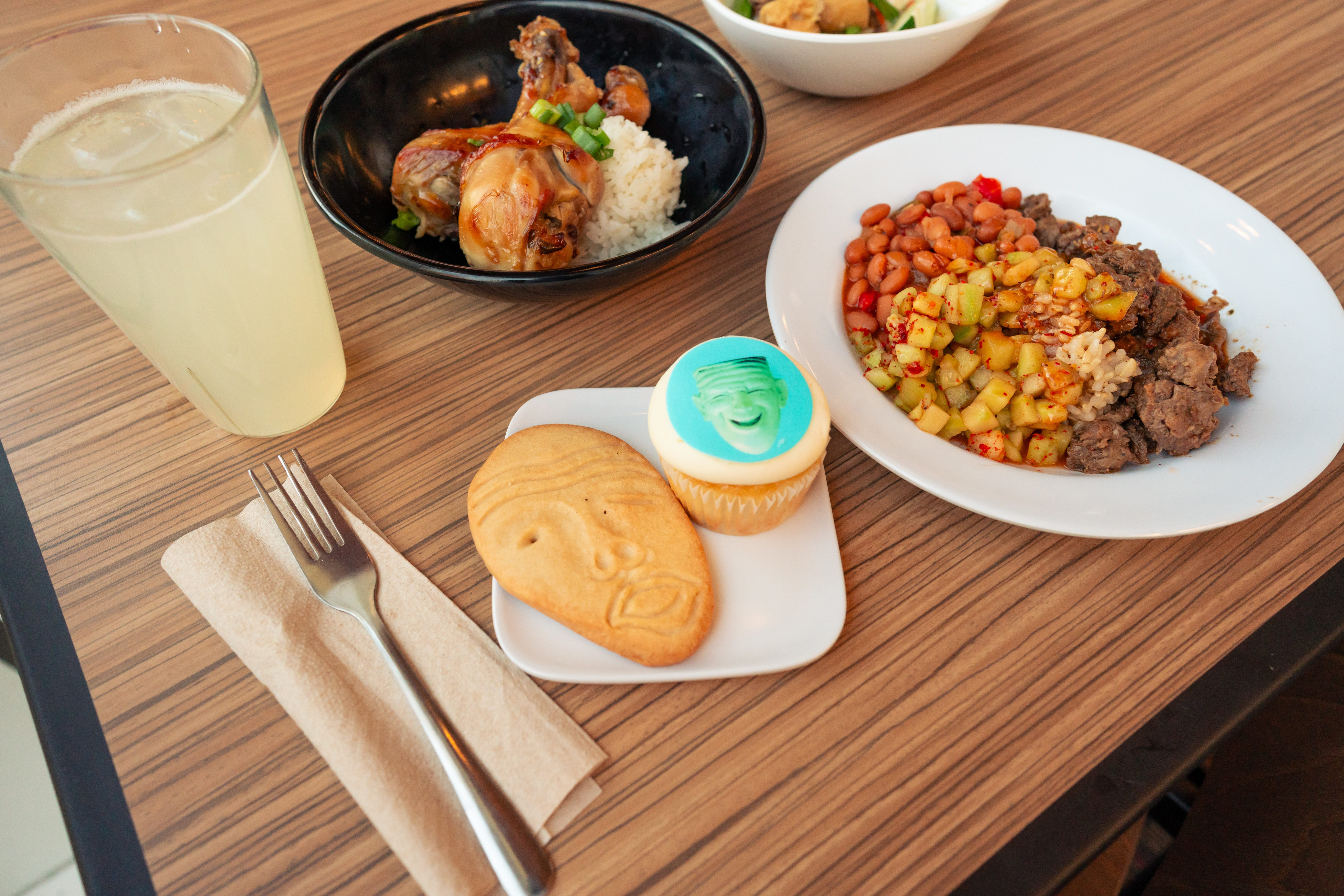An overhead photo featuring a full dining set and meal, featuring egghead-shaped cookies and cupcakes