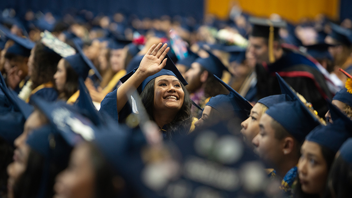 student waves at uc davis commencement