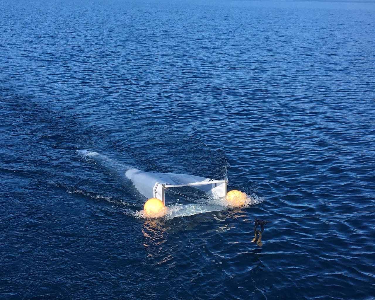 Photo of a small net with yellow floats on it being dragged across the surface of a lake.