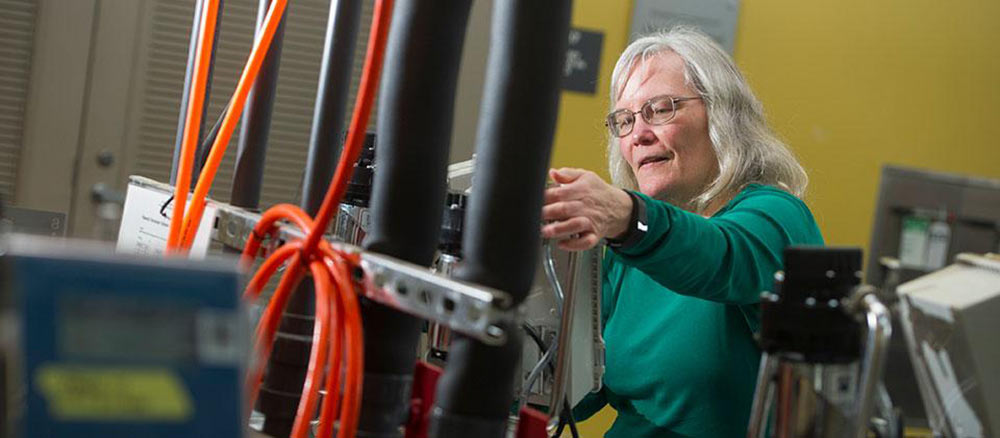 Linda works behind technical equipment and cords at UC Davis.