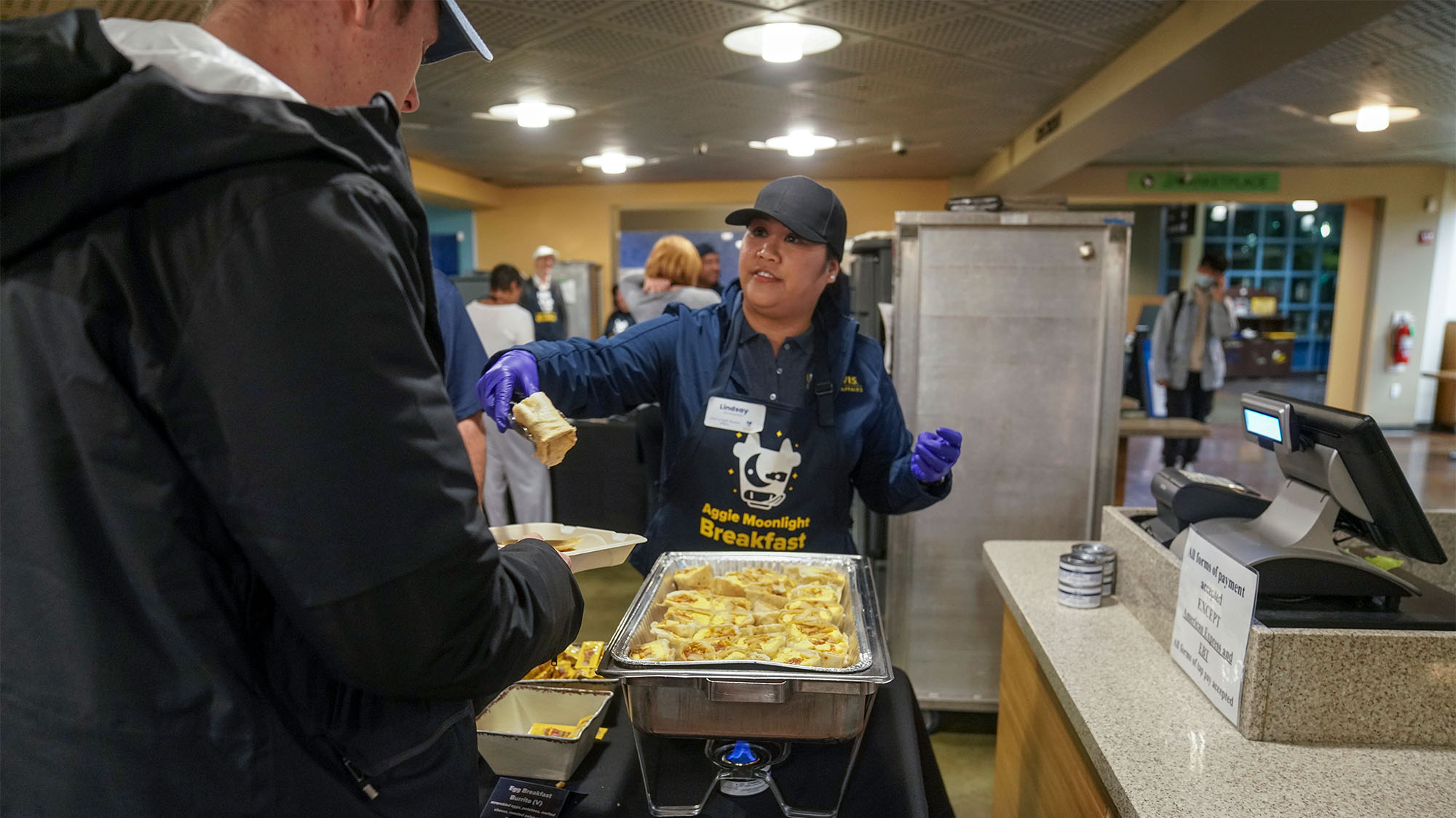 Woman serves breakfast burritos from warming tray