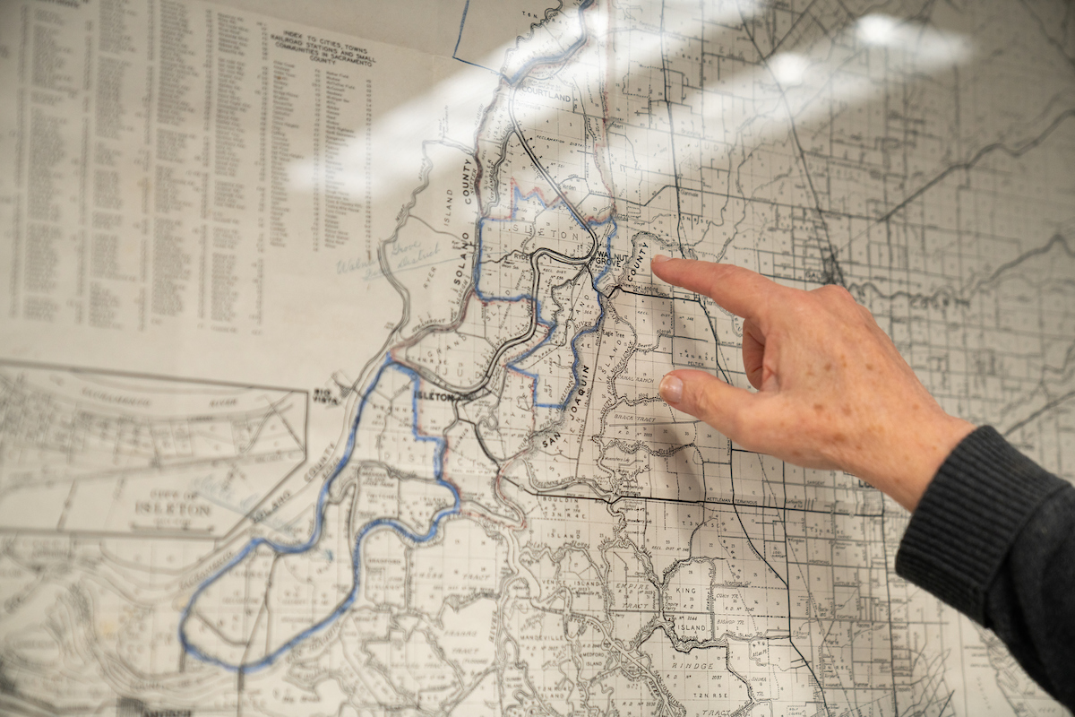 finger points to areas of map hanging on wall