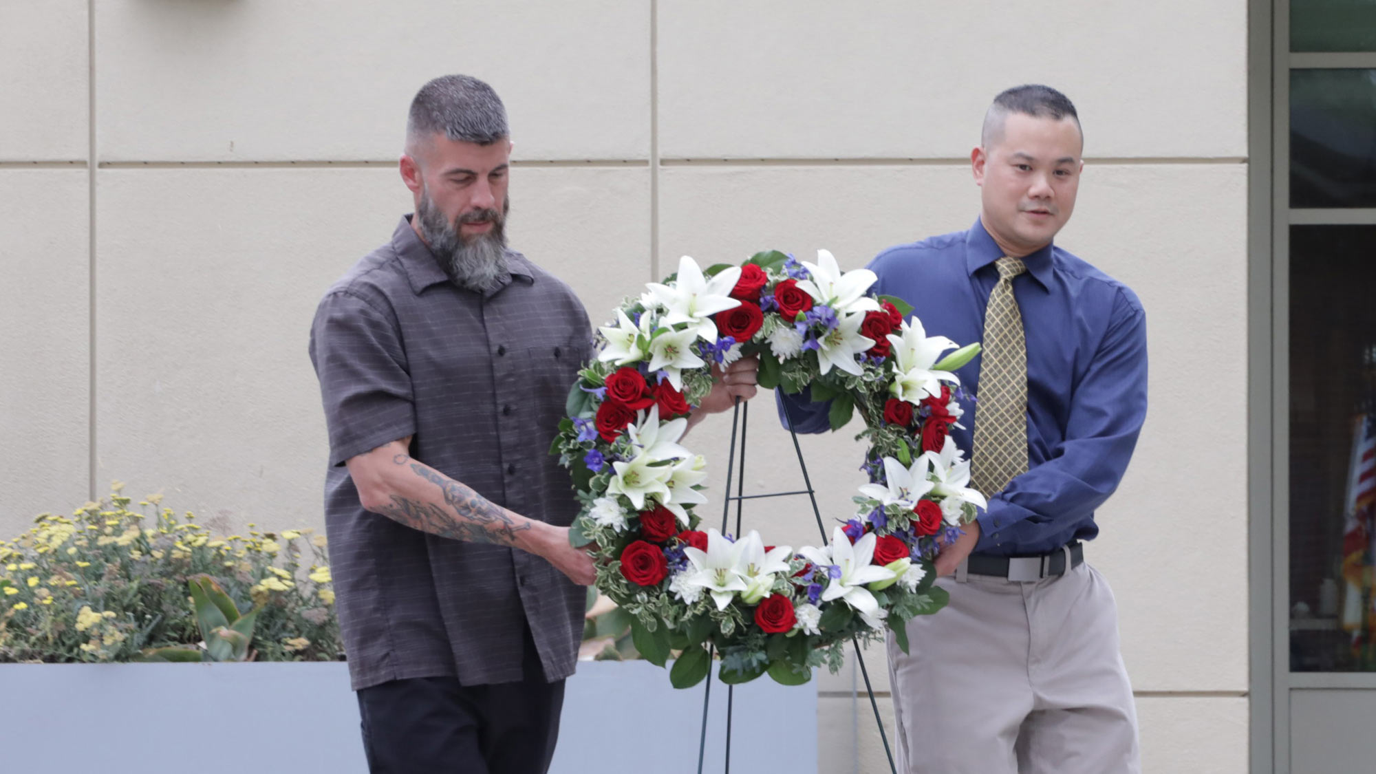 Two men carry red, white and blue wreath