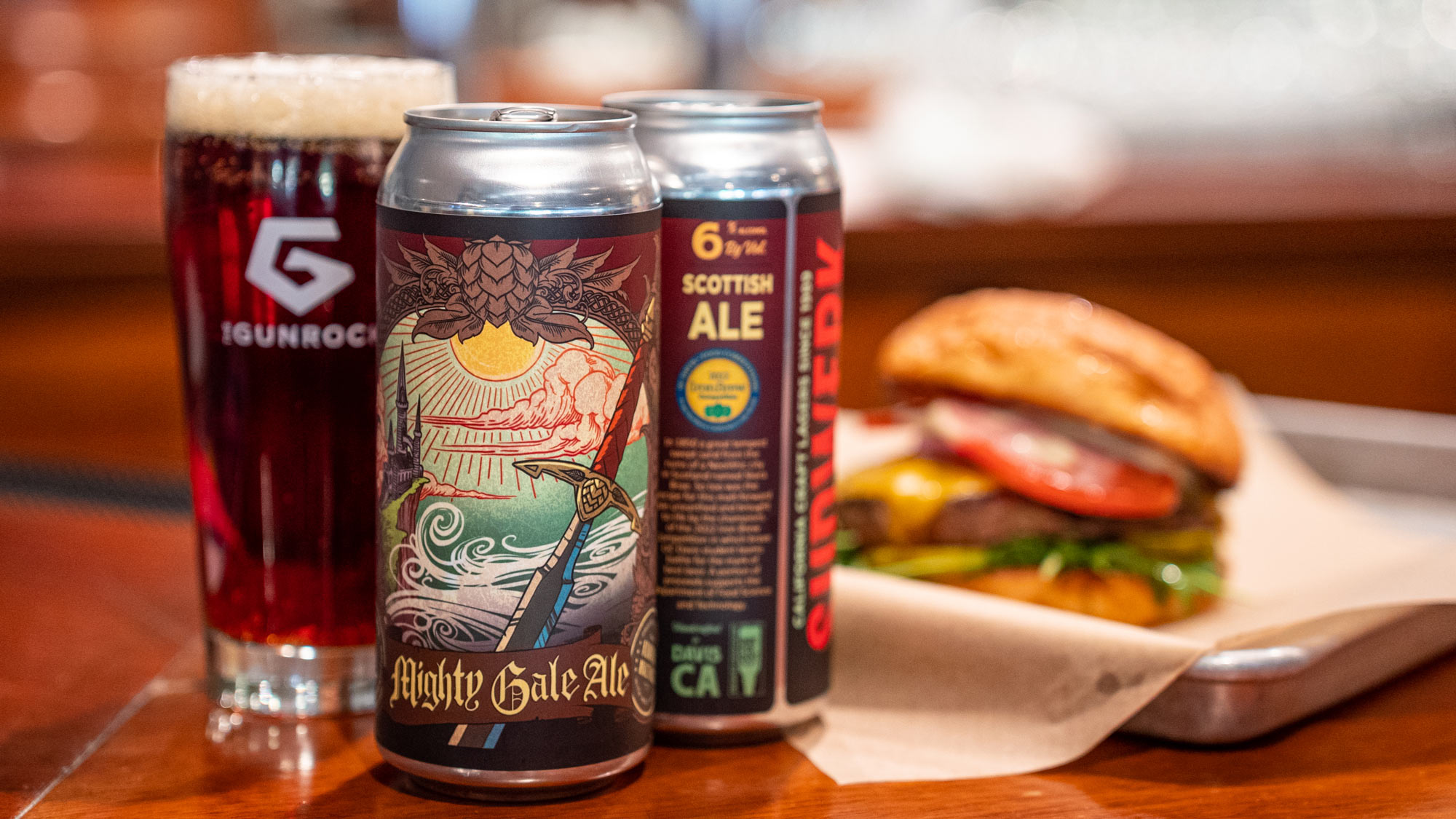 Mighty Gale Ale in can and Gunrock-logo glass, alongside hamburger on a bun