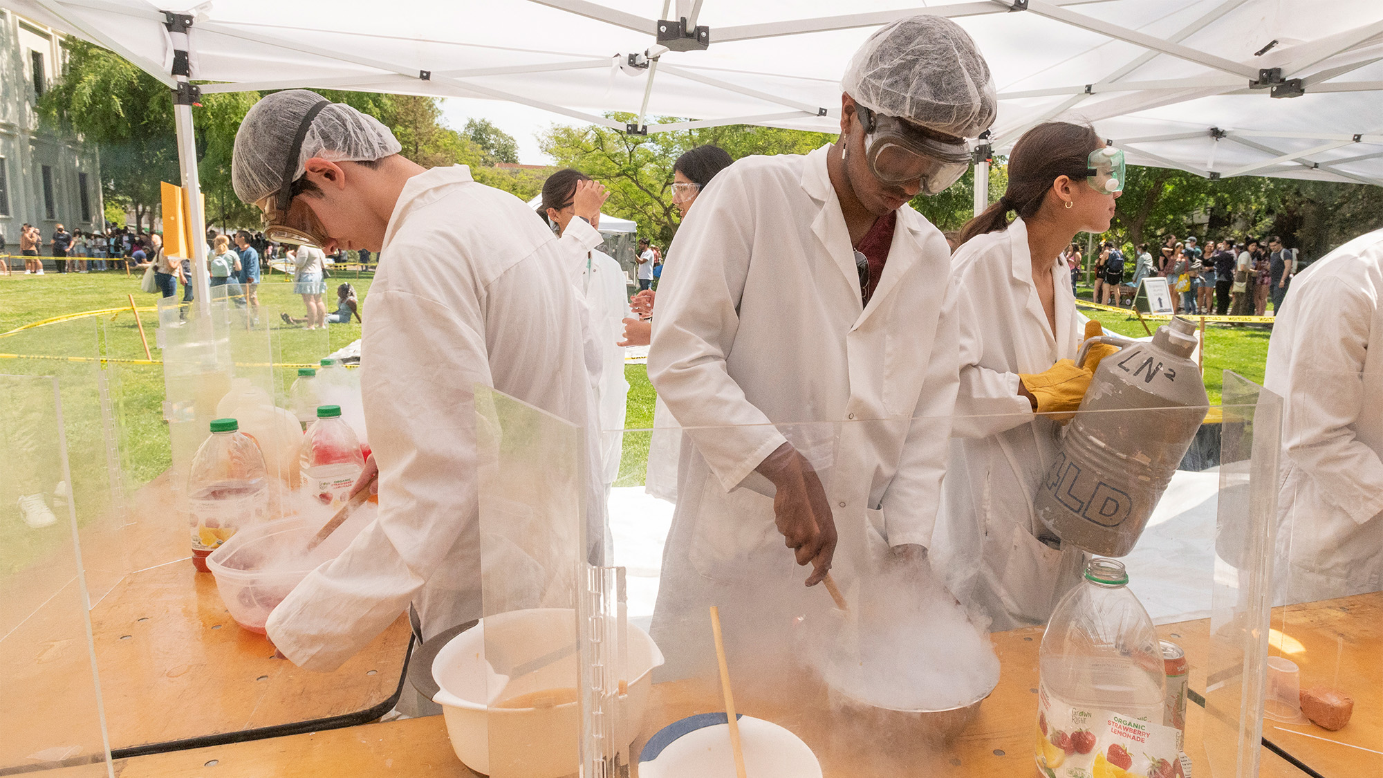 Students in lab coats make bowls of ice cream using liquid nitrogen.