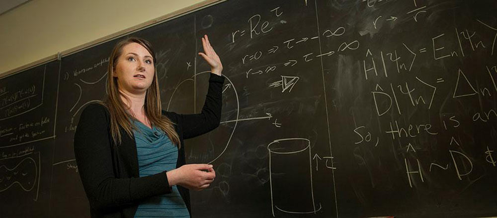 Rachel stands in front of a chalkboard while lecturing at UC Davis