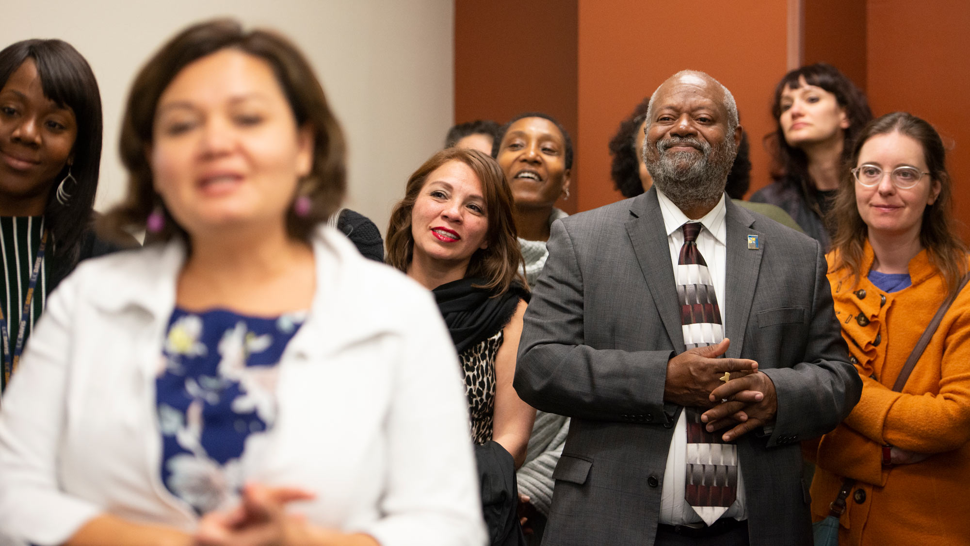 Rahim Reed smiling, surrounded by Office of Diversity, Equity and Inclusion staff while listening to a speaker at DEI open house.