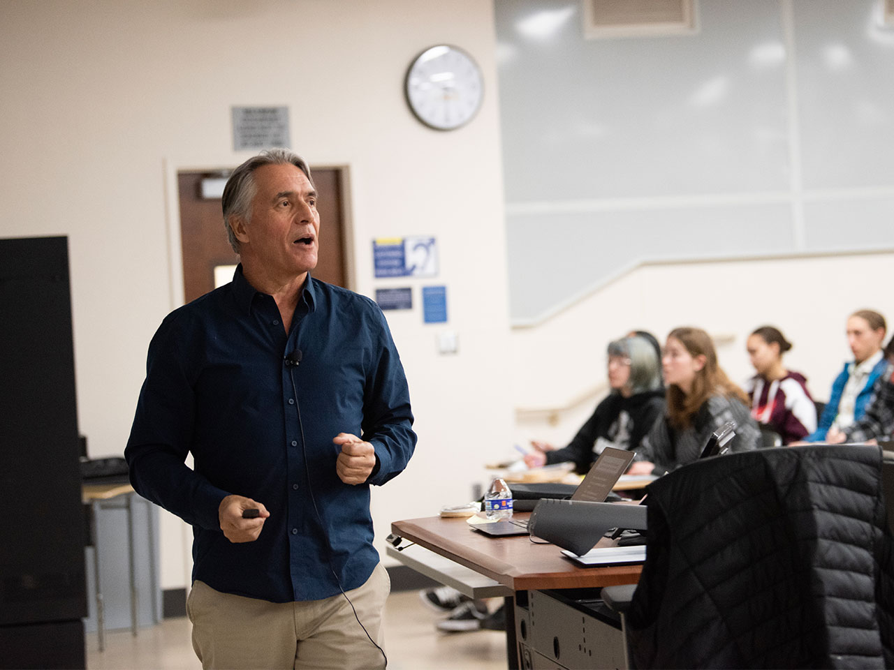 A UC Davis professor in a dark blue button-up shirt teaches a class.