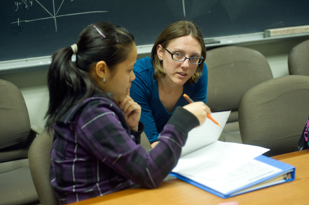 A professor in front of a blackboard chats with a student at UC Davis. 