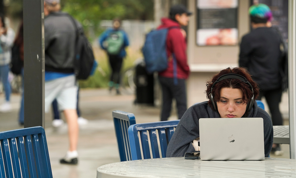 A student uses her laptop computer outside of California Hall at UC Davis. 
