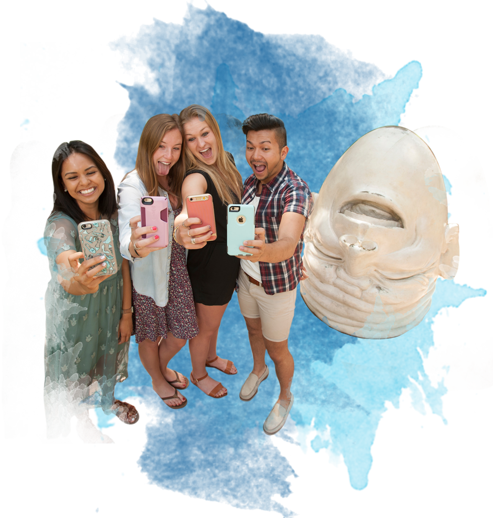 Four UCD students take a selfie next to one of our famous egghead statues.