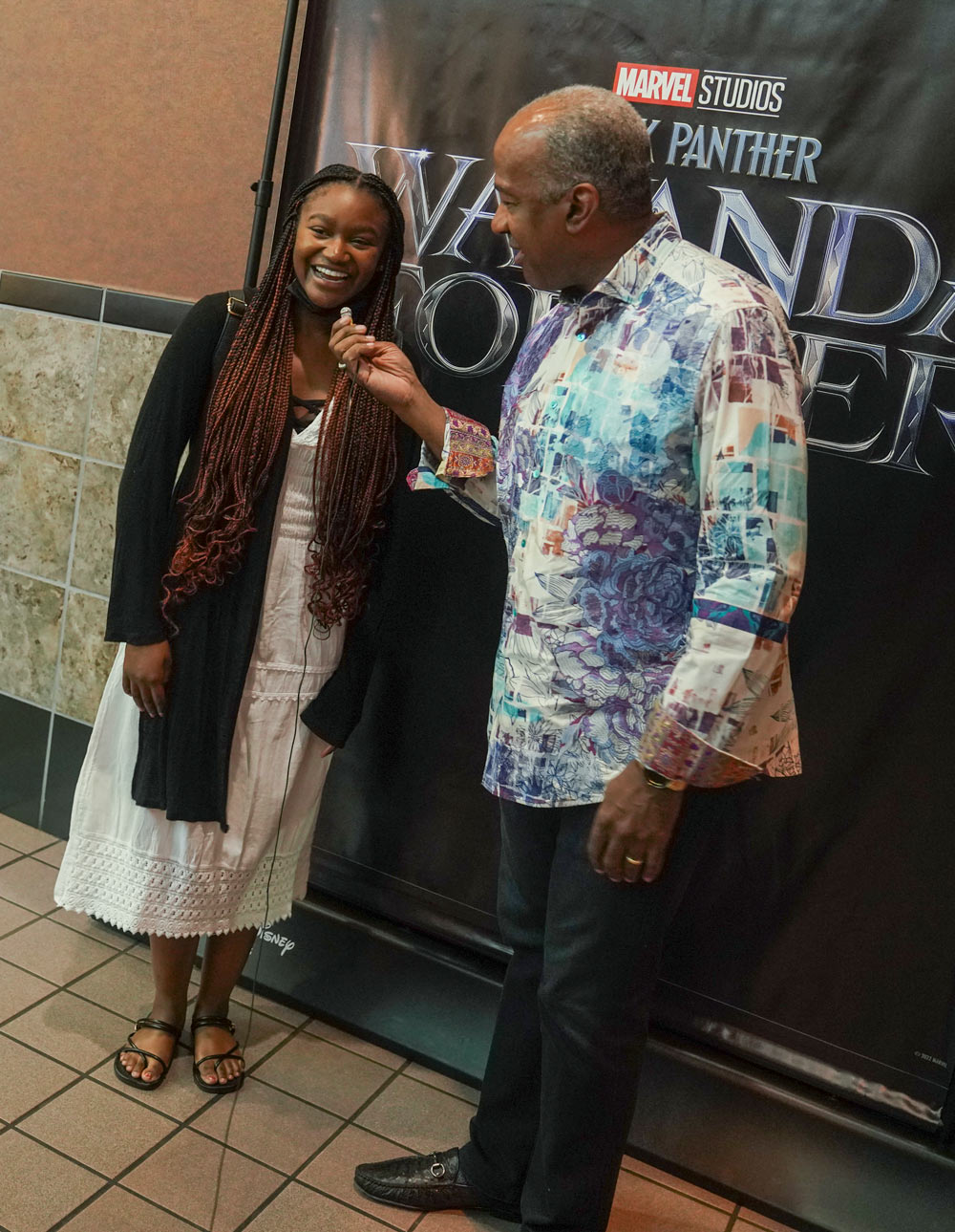 Chancellor May interviews a student in front of "Wakanda Forever" poster