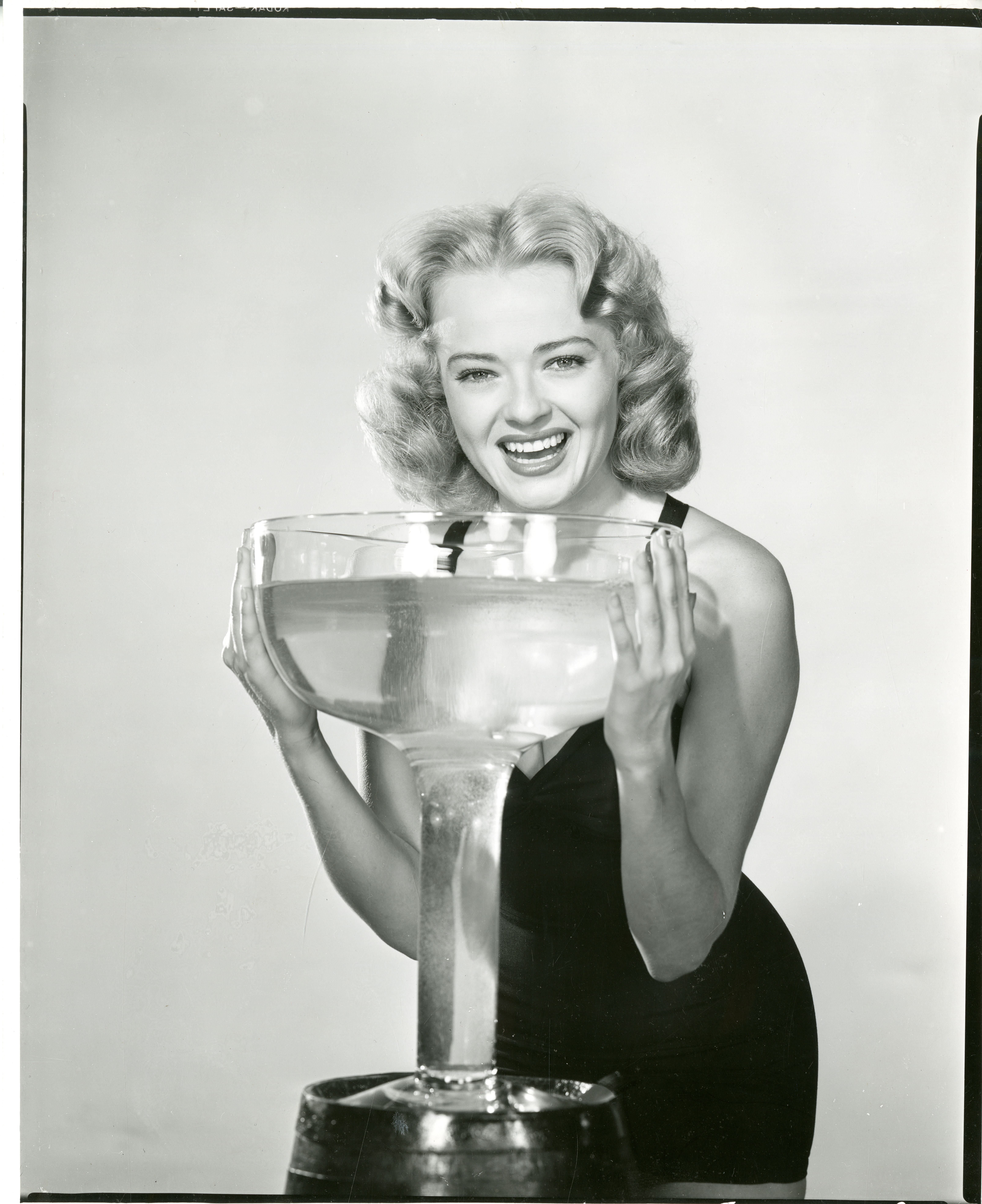 Vintage black-and-white photograph with woman and giant wine glass.