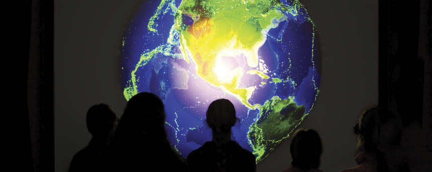 Viewers stand in front of a screen showing a digital image of the globe